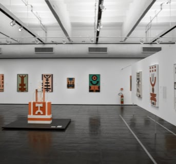 Abstract paintings in Native American style presented in the gallery.